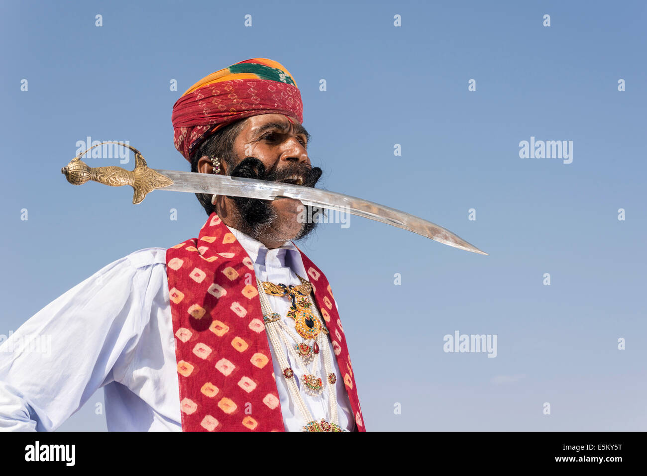 Uomo locale in posa con la spada nella bocca, Rajput persone, Bikaner, Rajasthan, India Foto Stock