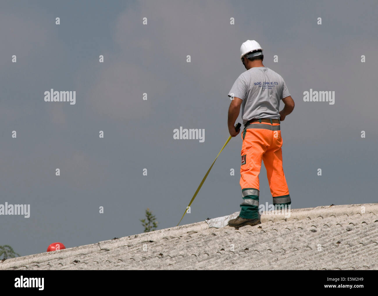 Lavoratore di manutenzione a lavorare sul tetto con nastro di misurazione Foto Stock