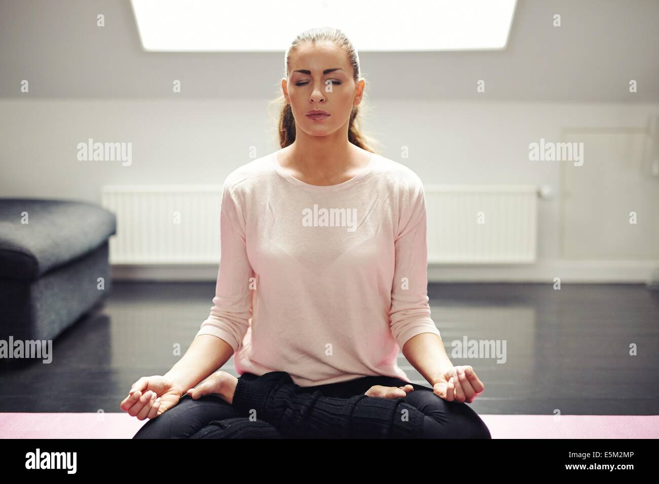 Ritratto di donna bella esercitazione. In un momento di relax a casa con lo yoga allenamento. Montare caucasian modello femminile nella meditazione. Foto Stock