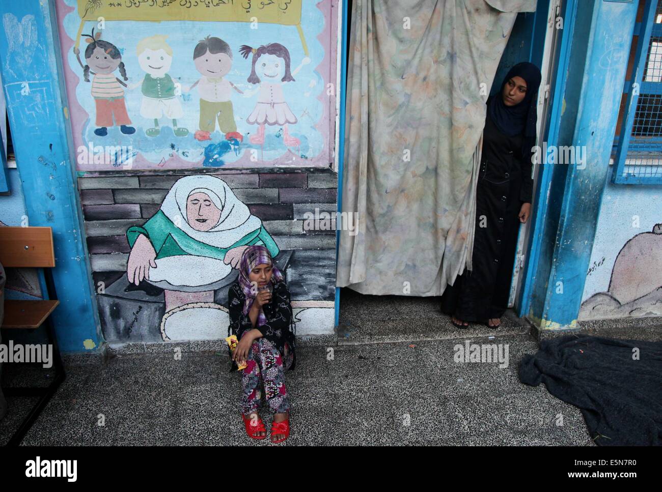 La città di Gaza, Striscia di Gaza, Territori palestinesi. Il 4° agosto 2014. Un spostato Ragazza palestinese beve un tè presso le Nazioni Unite (ONU) Scuola di Beit Lahia nel nord della Striscia di Gaza il 4 agosto, 2014, dove essi hanno trovato rifugio dopo essere fuggiti dalle loro case a causa di bombardamenti israeliani su assediato in territorio palestinese. Israele terrà il suo fuoco nella maggior parte della striscia di Gaza per un periodo di sette ore di ''finestra umanitaria'', il militare ha detto, quattro settimane nel suo sanguinoso conflitto con Hamas Credito: Ezz Al-Zanoun APA/images/ZUMA filo/Alamy Live News Foto Stock