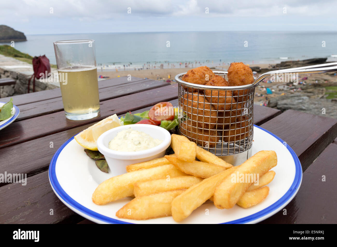 Un pasto di Pub di scampi, trucioli e sidro al di fuori del porto William Inn con la spiaggia a Trebarwith Strand dietro, Cornwall Regno Unito Foto Stock