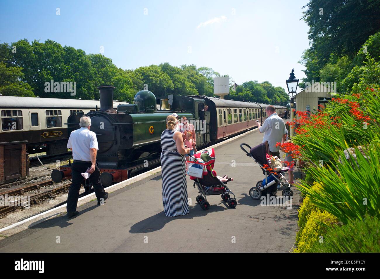 I passeggeri di guardare un treno a vapore che arrivano a Bodmin stazione generale sull'Bodmin e Wenford Railway, Cornwall, Regno Unito Foto Stock