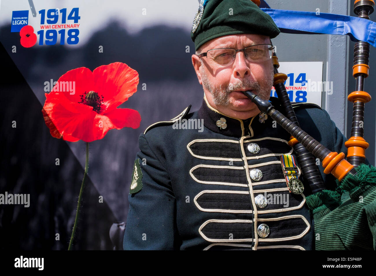 Londra, UK, 4 agosto 2014. Campi di battaglia, terre di pace, una mostra di fotografie di Michael San Maur Sheil, che ha passato gli ultimi sette anni ad esplorare i campi di battaglia cercando di catturare la storia e le emozioni di questo periodo drammatico è ufficialmente aperto in St James Park. Nella foto: un piper da 'D' (London Irish) Compagnia del reggimento di Londra esegue all'apertura ufficiale della mostra. La mostra è sul display di fronte Horse Guards, adiacente alle guardie Memorial finché il giorno dell'Armistizio nel novembre 11th. Credito: mark phillips/Alamy Live News Foto Stock