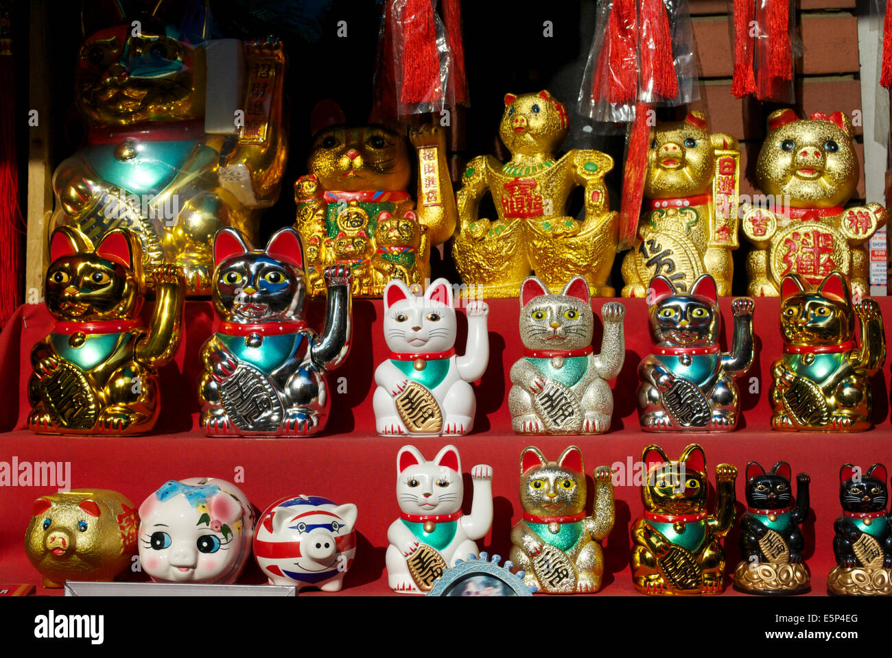 Primo piano di Maneki Neko giapponese al sole che invita i gatti in una vetrina di un negozio a Chinatown, Soho, Londra, Inghilterra, Regno Unito Foto Stock