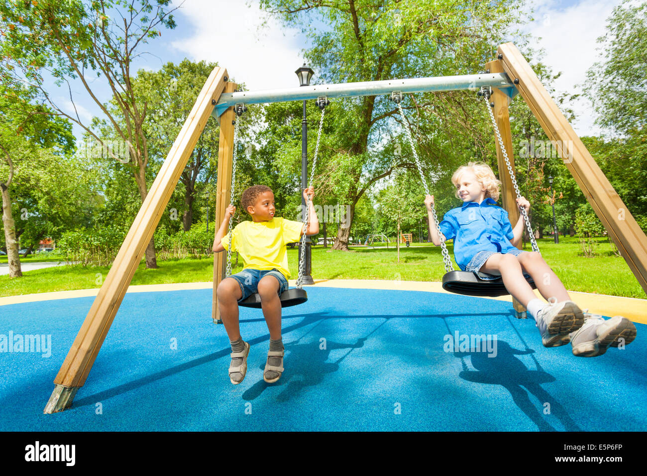 I bambini su altalene fissando ogni altro e sit Foto Stock