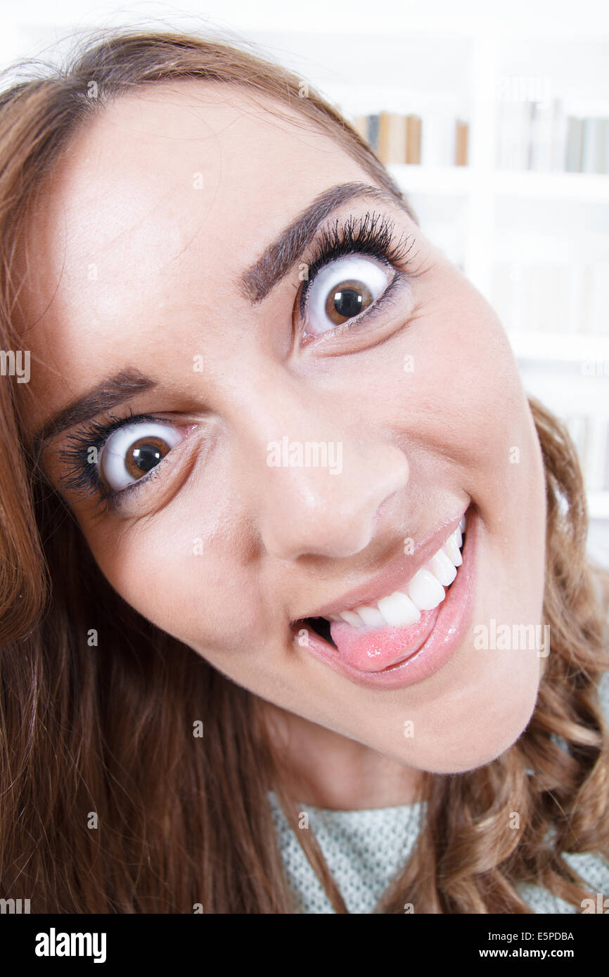 Giovane donna con la lingua fuori e gli occhi aperti, crazy mad faccia espressione, atmosfera da salotto Foto Stock