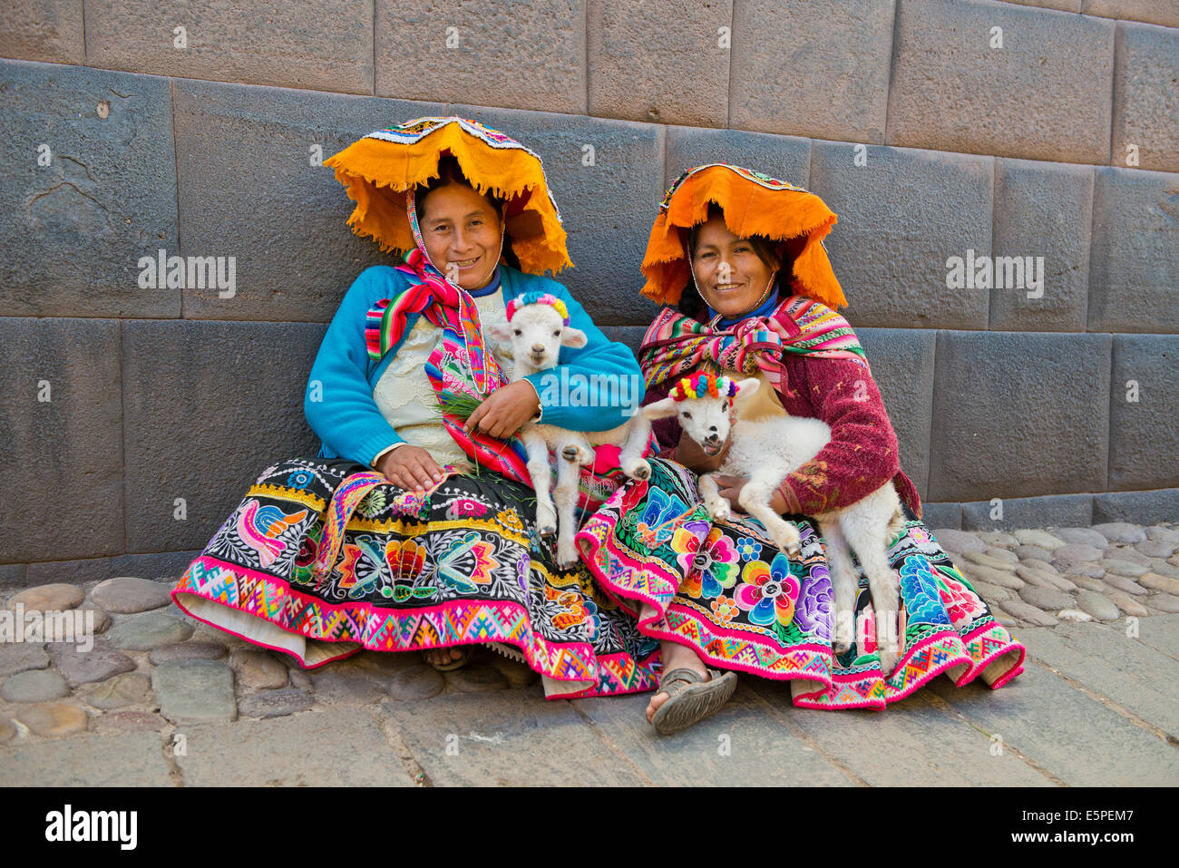 Due donne Quechua in abito tradizionale azienda agnelli nel loro armi, seduto a terra, Provincia di Cusco, Perù meridionale, Perù Foto Stock