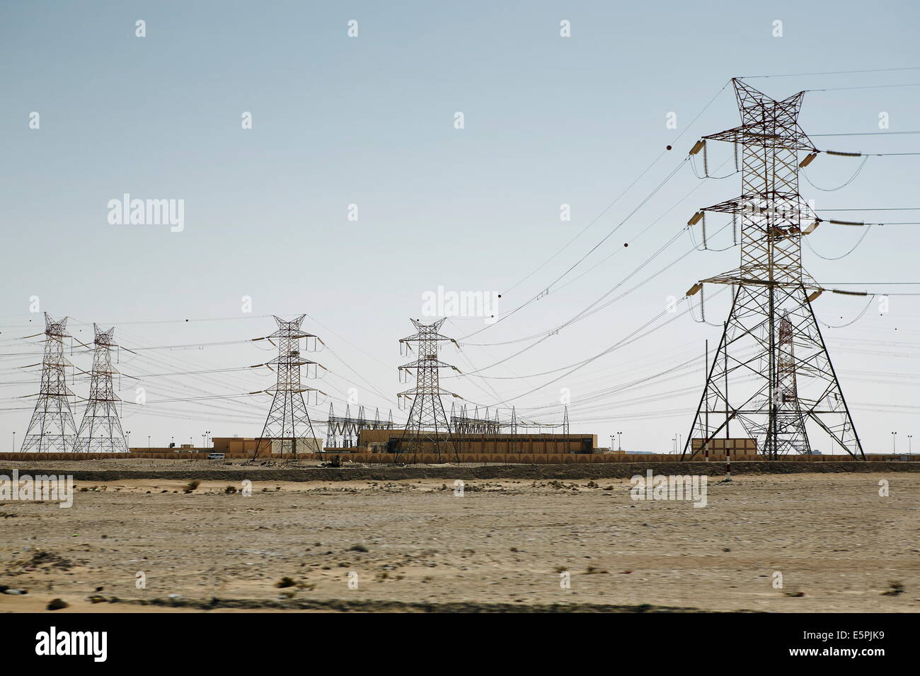 Elettricità tralicci dominano il piatto paesaggio arido, puntando alla civiltà da qualche parte, Qatar, Medio Oriente Foto Stock