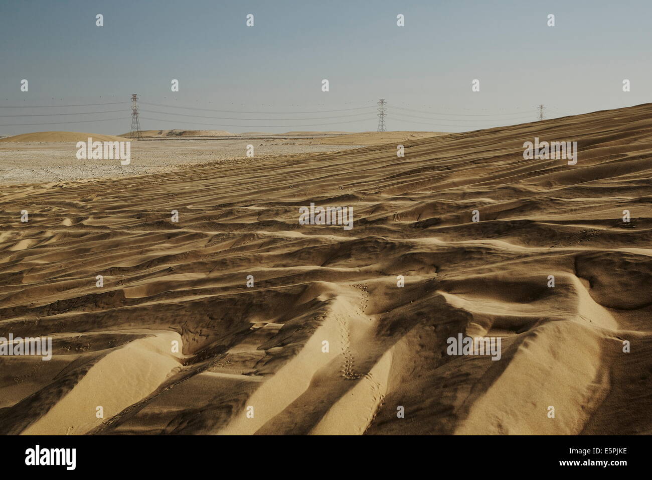 Le dune di sabbia e l'elettricità tralicci dominano il paesaggio del deserto del Qatar, Medio Oriente Foto Stock