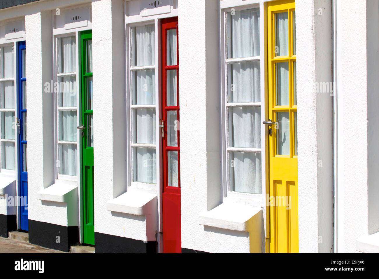 Riga della pittoresca spiaggia di capanne sulla spiaggia Porthgwidden, St Ives, Cornwall Inghilterra. In prossimità della porta dipinta di rosso verde giallo e blu Foto Stock