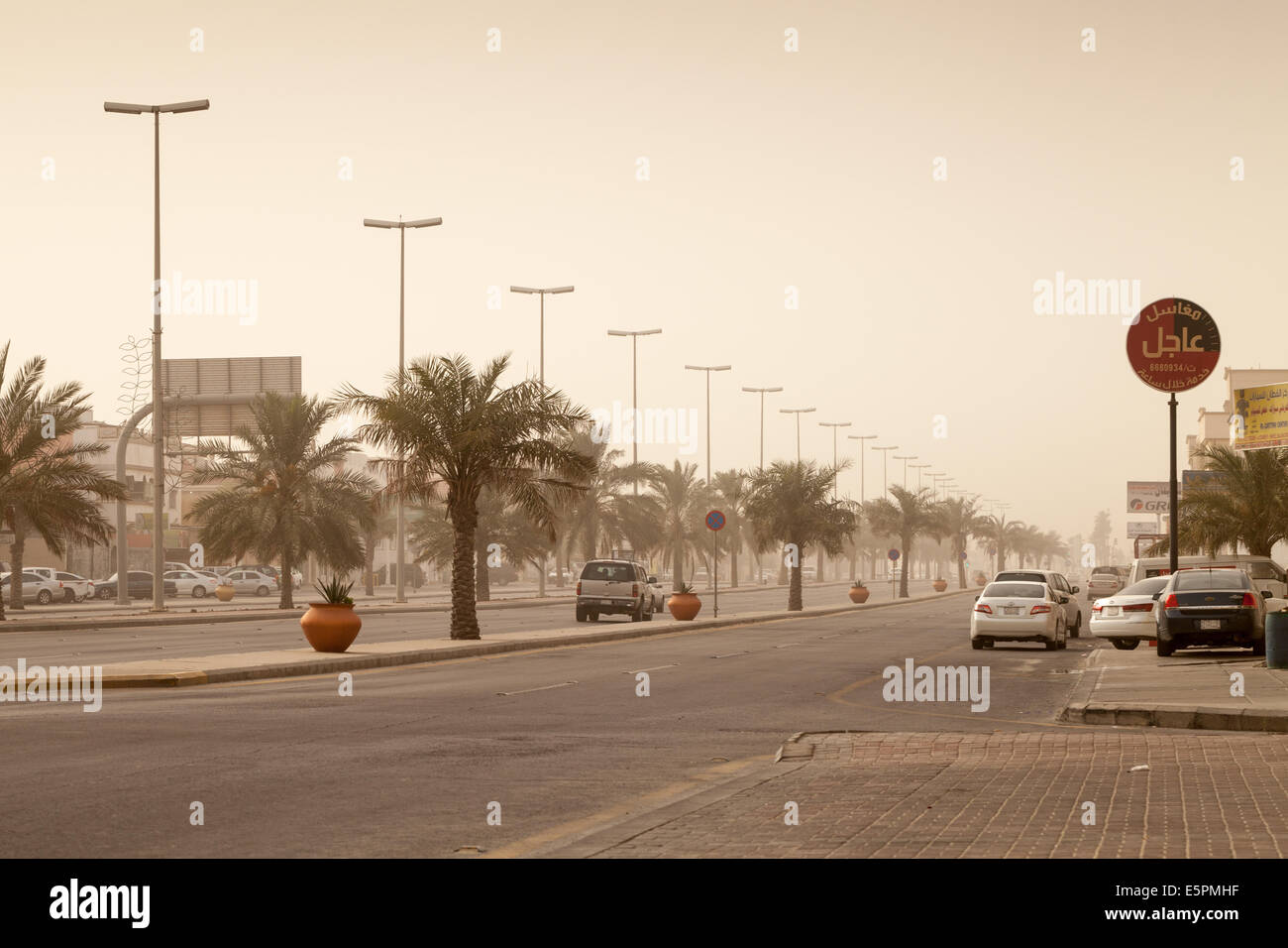 RAHIMA, Arabia Saudita - 11 Maggio 2014: Street view con le automobili e le palme, tempesta di polvere in Arabia Saudita Foto Stock