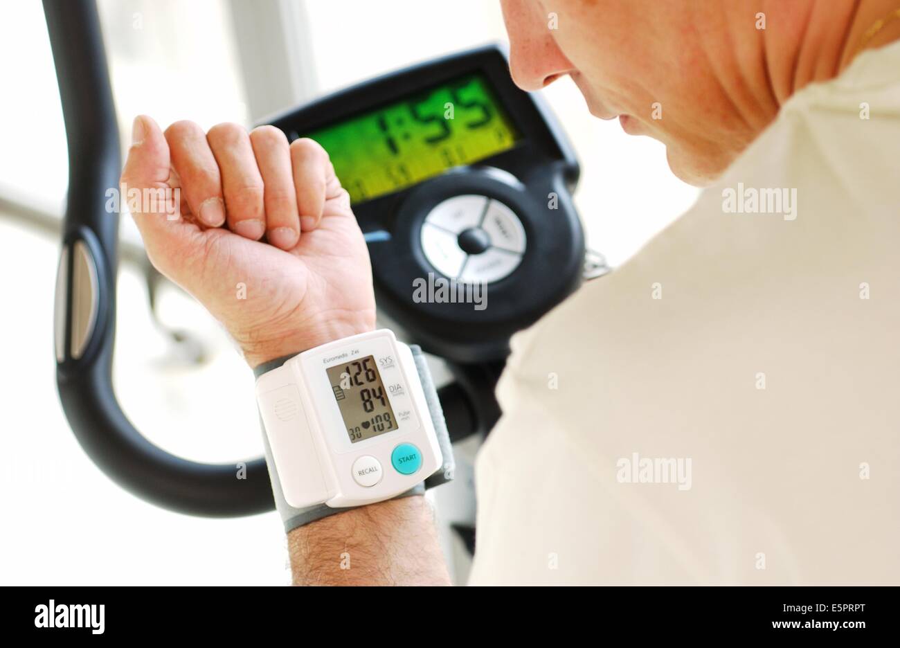 Monitoraggio uomo la sua pressione del sangue con un portatile di Sfigmomanometro digitale quando si pratica excercize bicicletta. Foto Stock