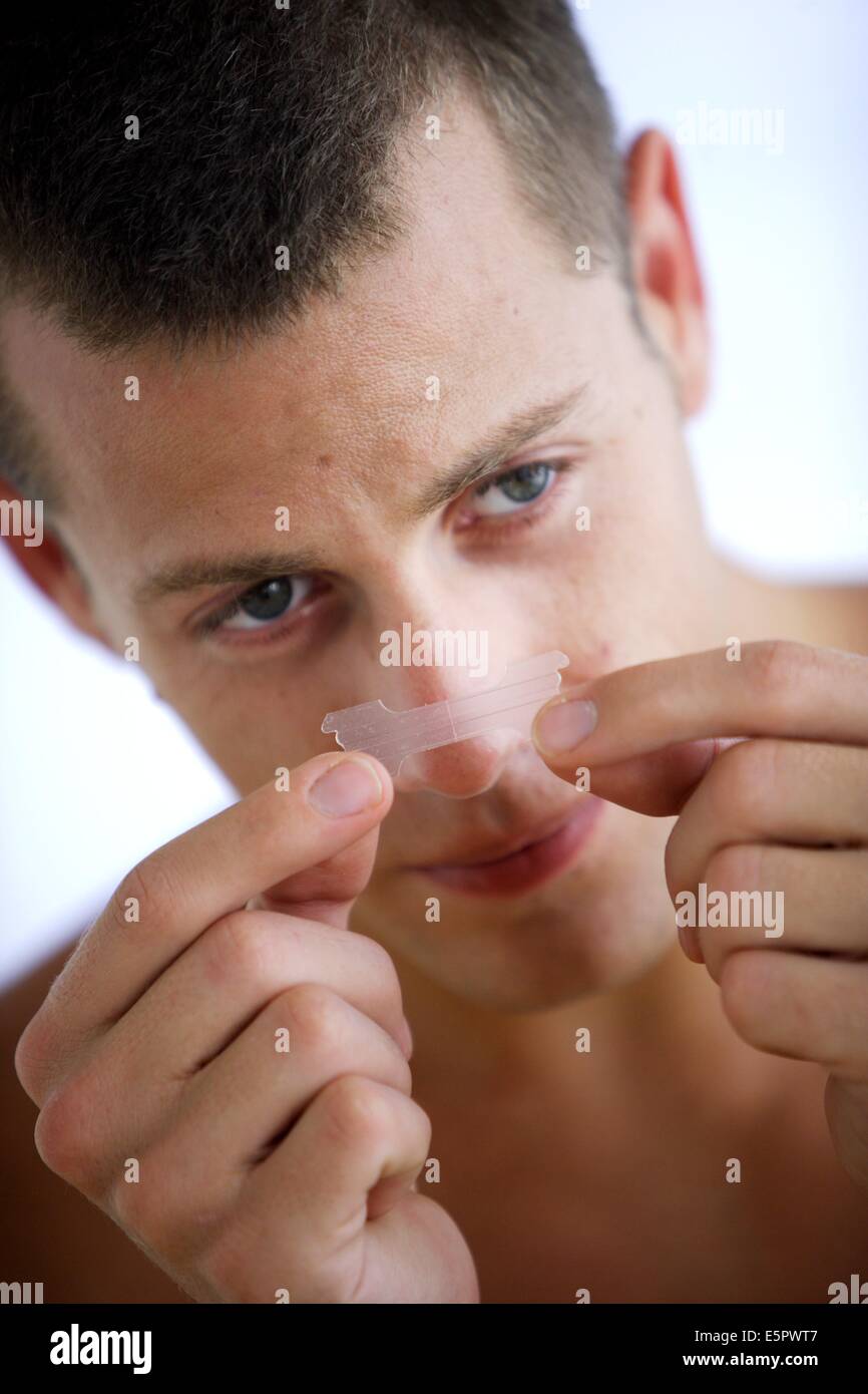 Uomo che indossa una striscia nasale, destinato a fornire sollievo tra rinite e febbre da fieno e raffreddori comuni consentendo un chiaro passaggio di Foto Stock