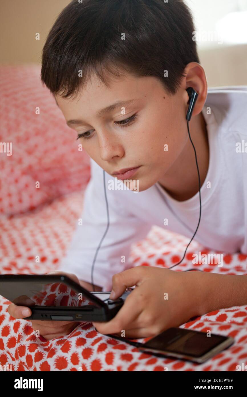 10 anno vecchio ragazzo giocare con la console per video game. Foto Stock