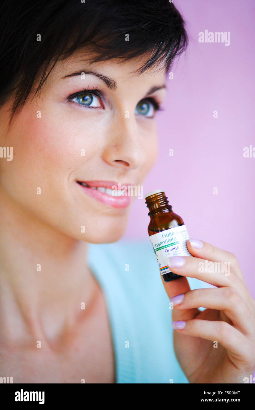 Donna annusare una bottiglia di olio essenziale. Foto Stock