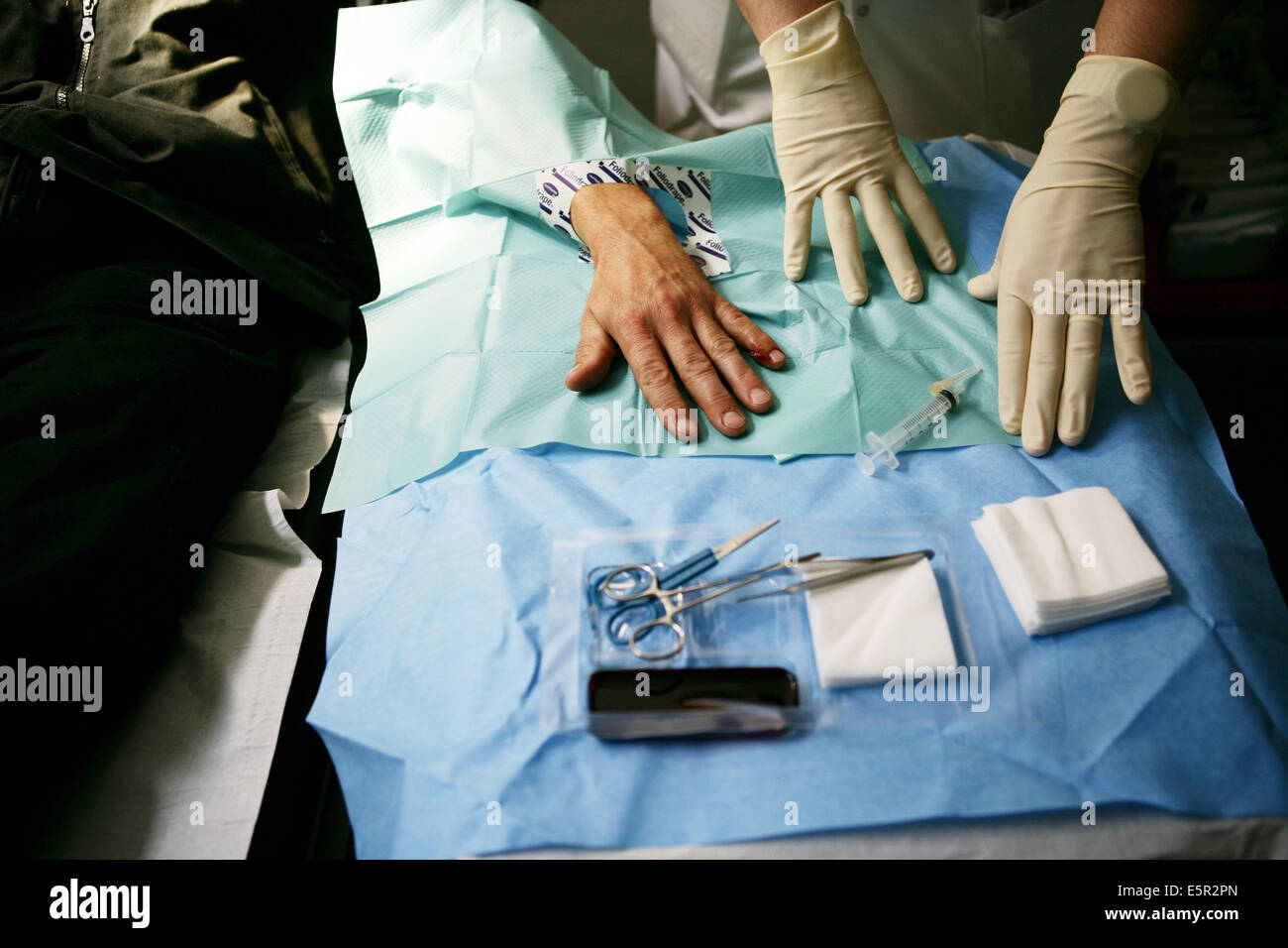 Medico cucitura fino alla mano di un paziente, dipartimento di emergenza, OSPEDALE Lariboisière, Parigi, Francia. Foto Stock