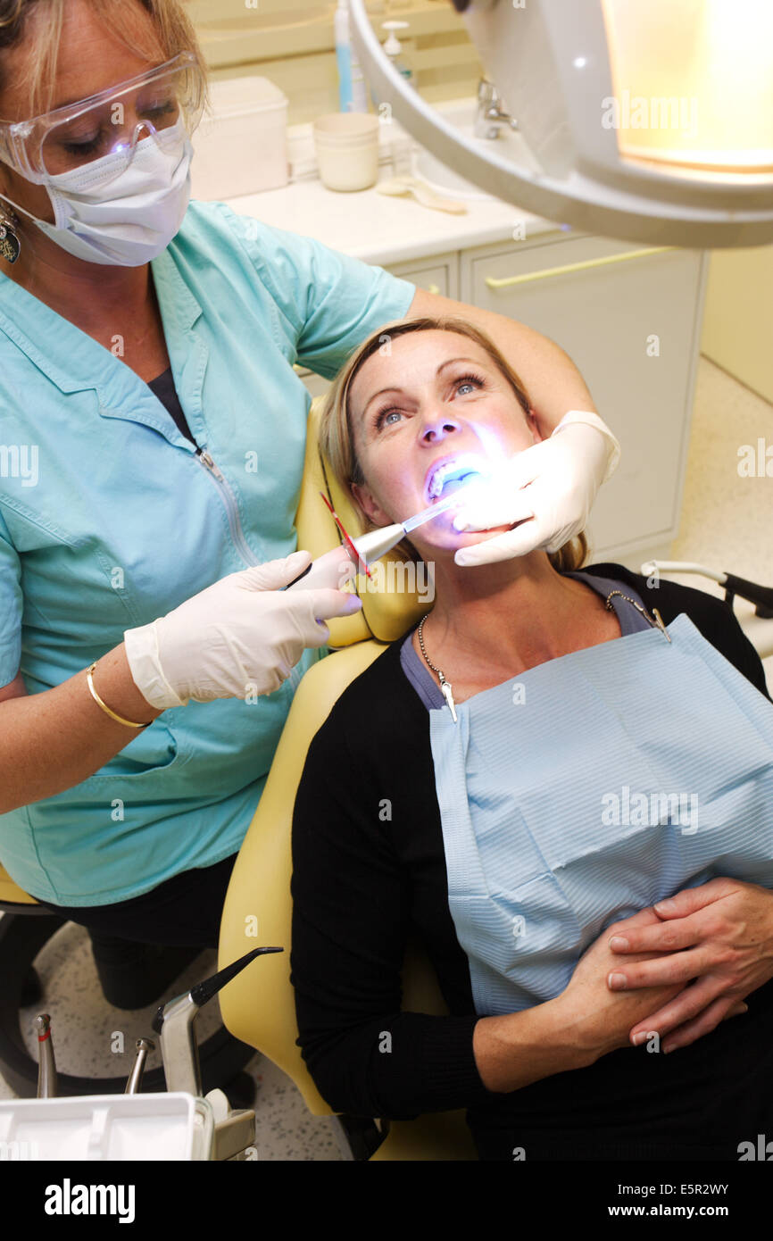Dentista usando luce ultravioletta per attivare i denti withening soluzione. Foto Stock