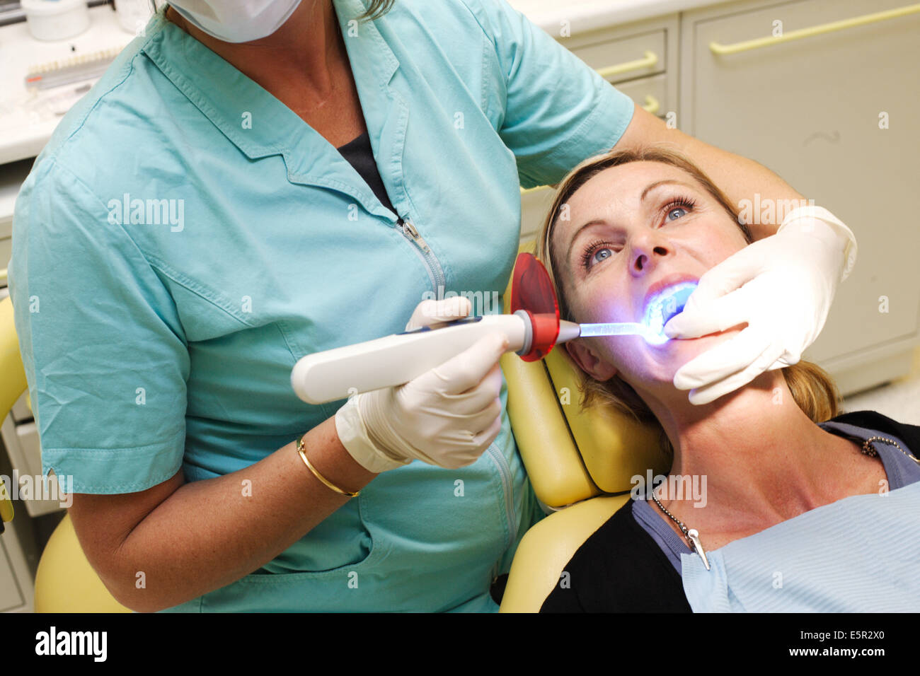 Dentista usando luce ultravioletta per attivare i denti withening soluzione. Foto Stock