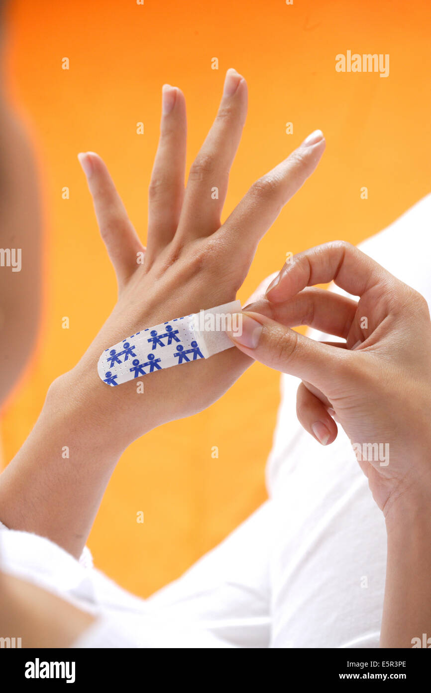 Donna mettendo una band-aiuto sulla sua mano. Foto Stock