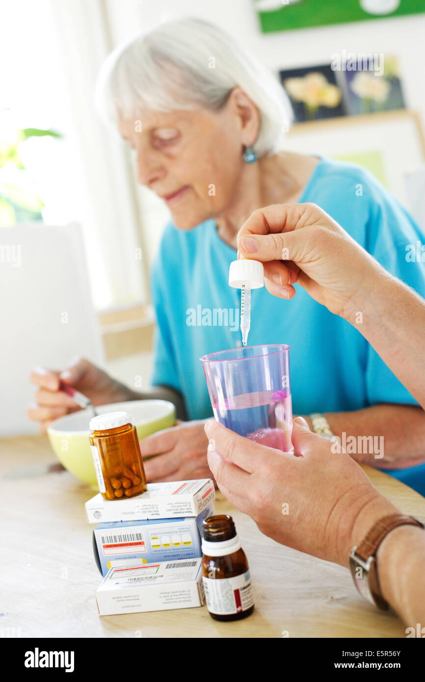 La donna che assiste 80 anno vecchia donna prendendo farmaci. Foto Stock