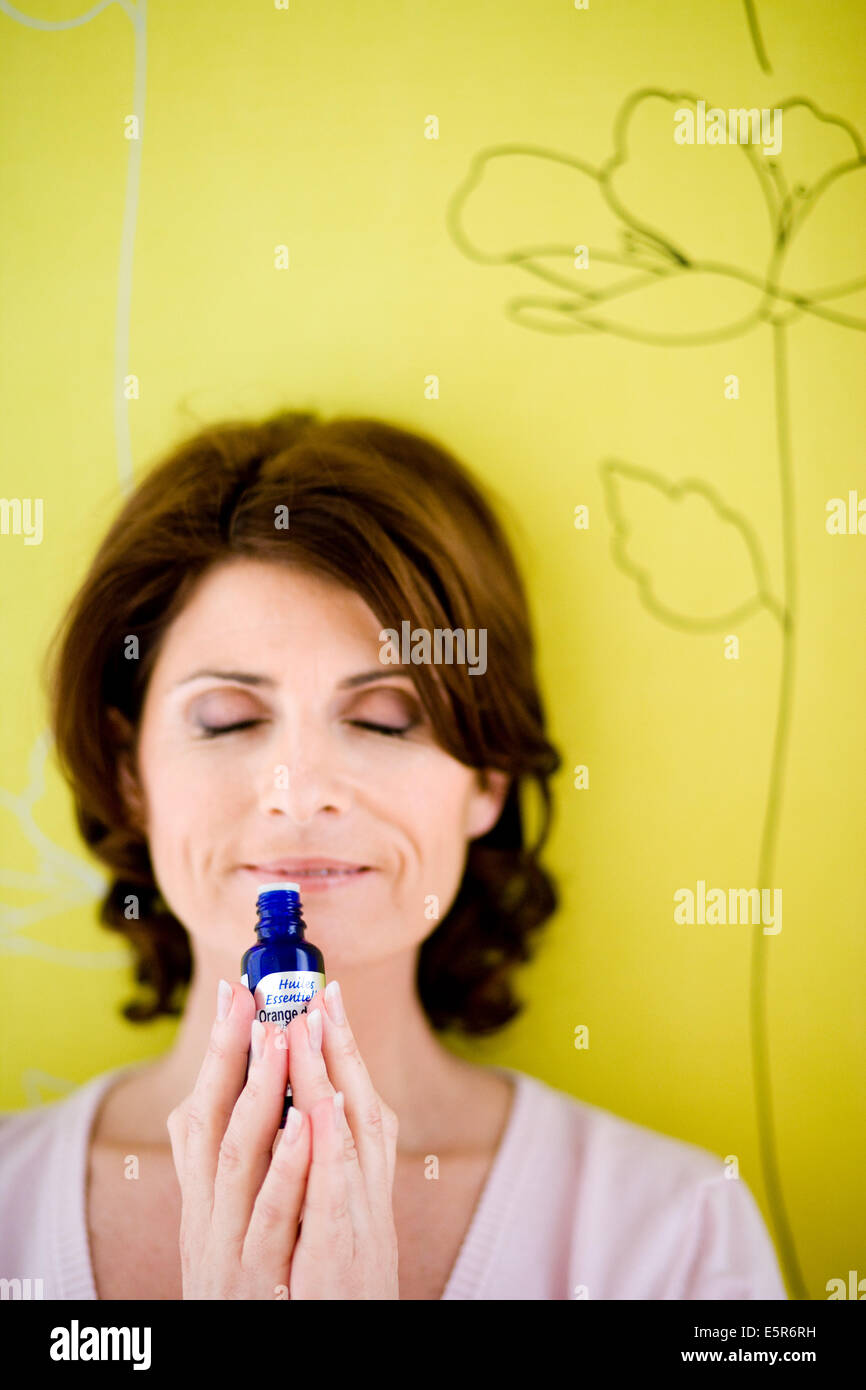 Donna annusare una bottiglia di olio essenziale. Foto Stock