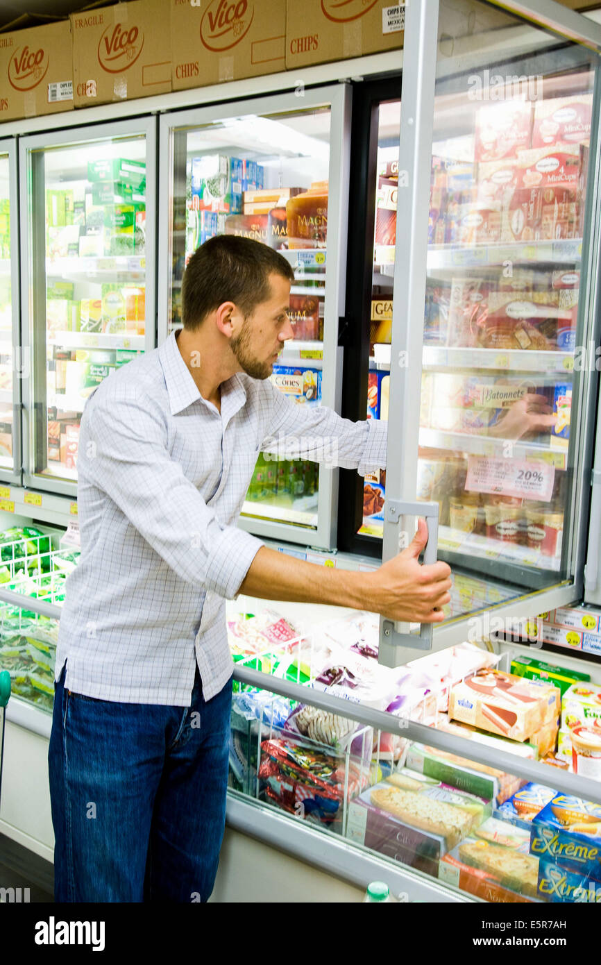 Uomo di shopping in alimenti congelati sezione nel supermercato. Foto Stock