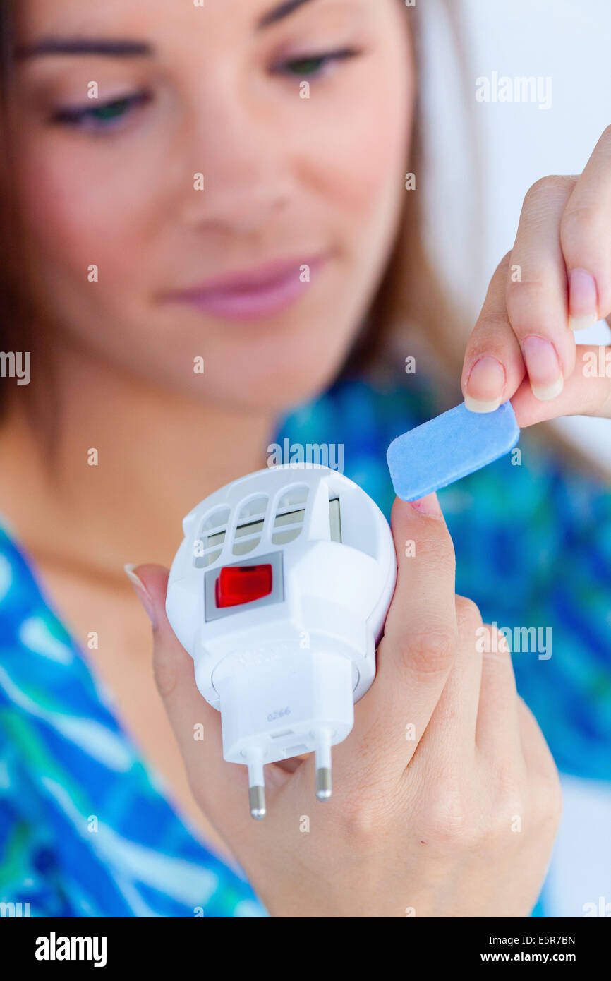 Donna che utilizza un elettrico mosquito diffusore. Foto Stock