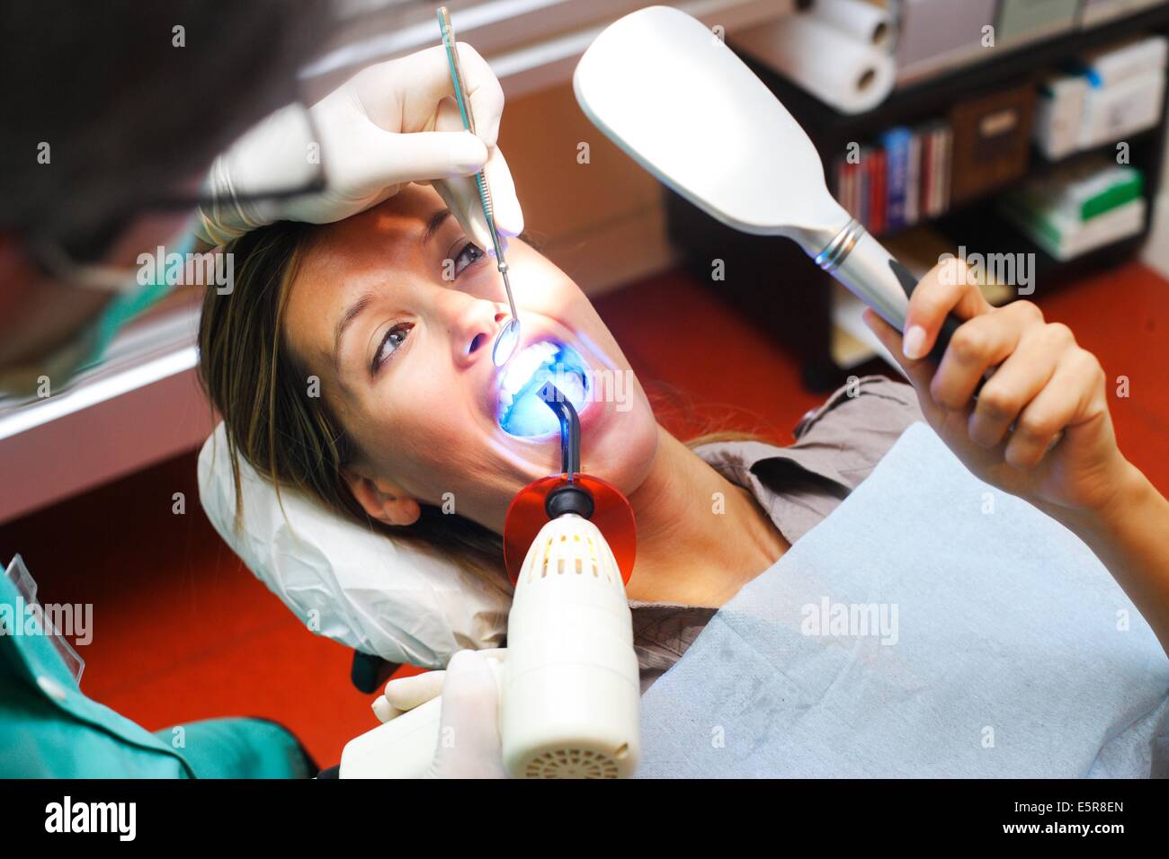 Dentista usando luce ultravioletta per attivare i denti withening soluzione. Foto Stock
