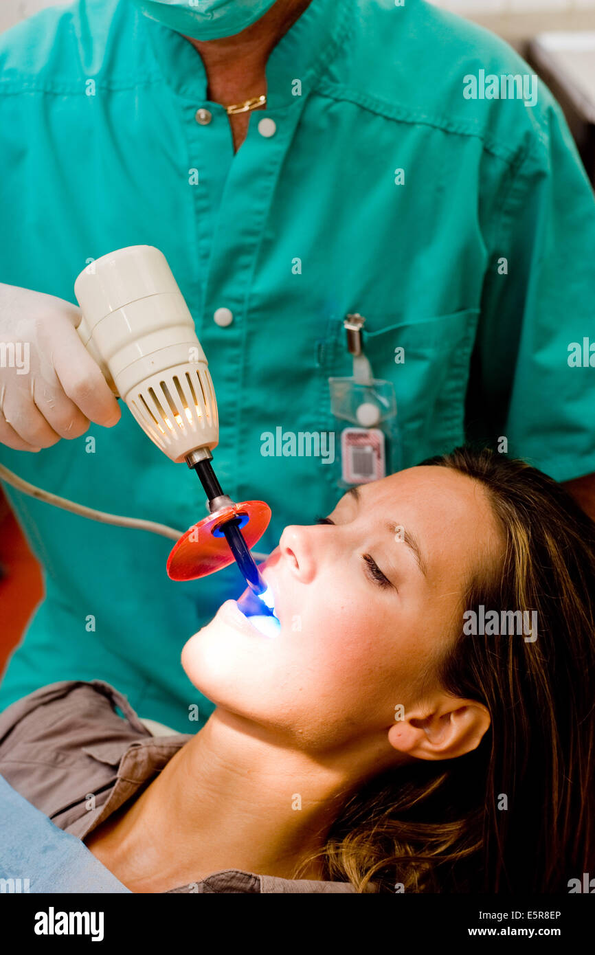 Dentista usando luce ultravioletta per attivare i denti withening soluzione. Foto Stock