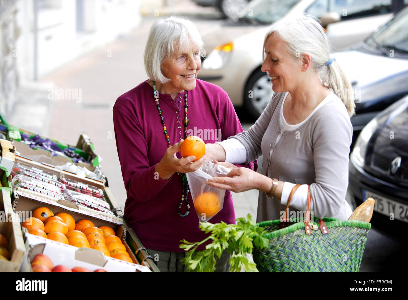 Donna prendendo 80 anno vecchia donna al mercato. Foto Stock