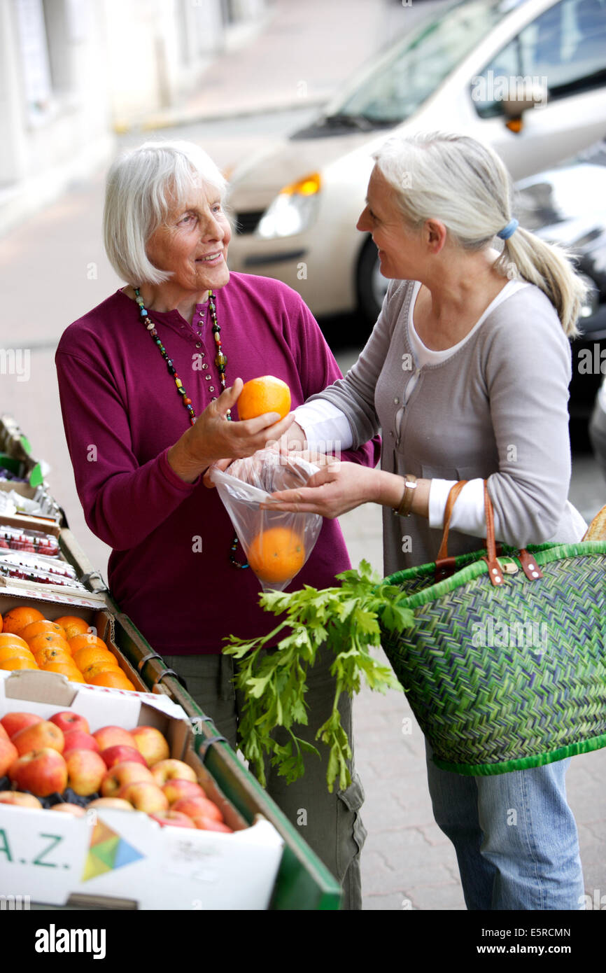 Donna prendendo 80 anno vecchia donna al mercato. Foto Stock