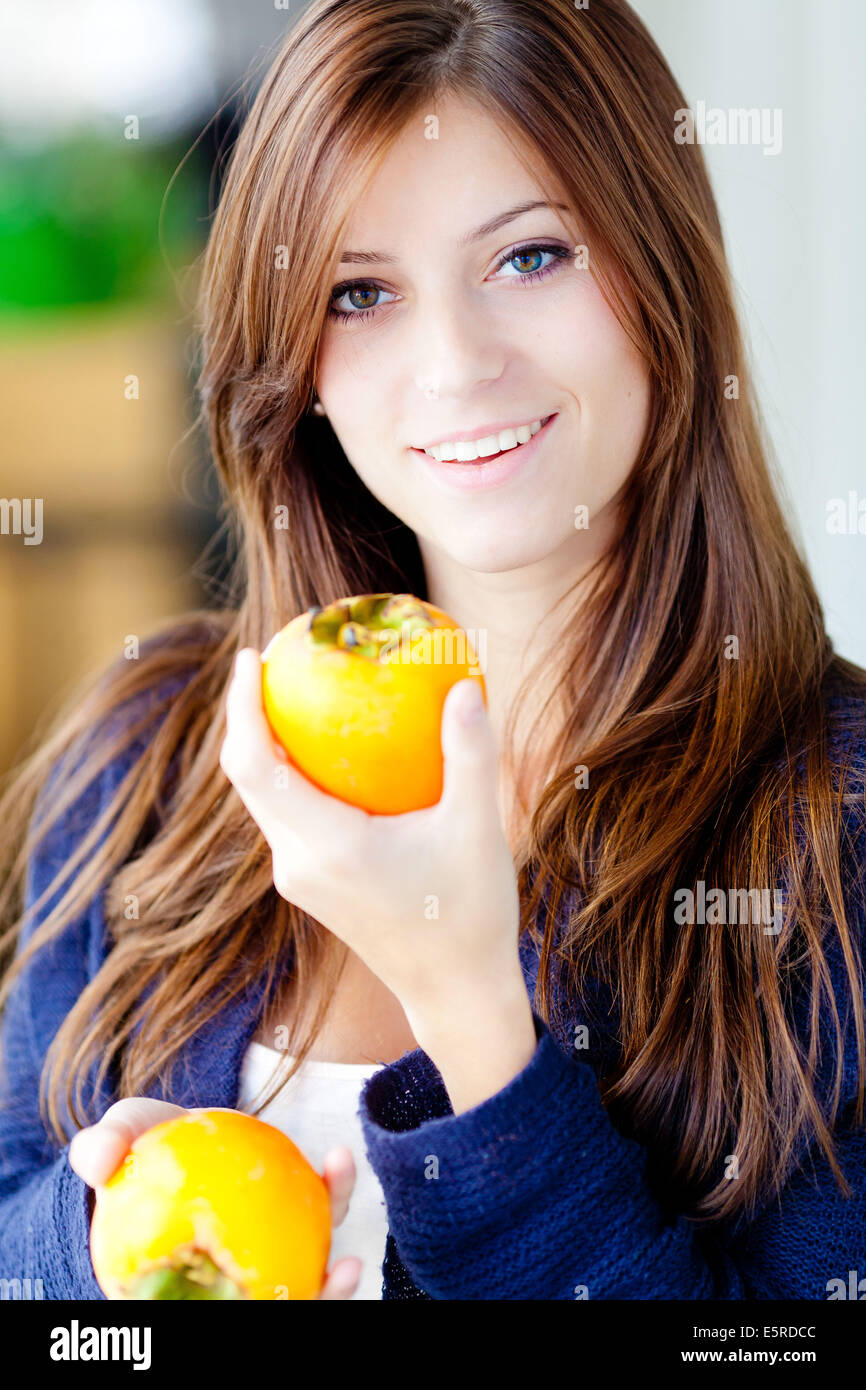 Donna di mangiare persimmon. Foto Stock