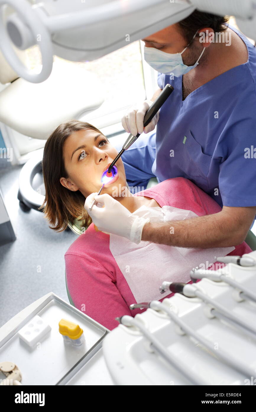 Dentista usando luce ultravioletta per impostare un amalgama fotosensibile (riempimento). Foto Stock