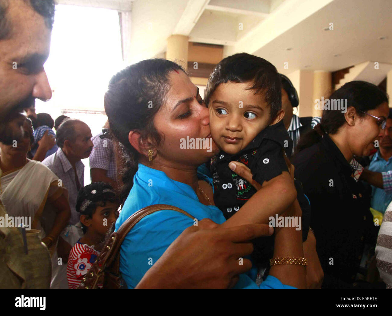 Kochi. 5 Ago, 2014. Uno dei 44 infermieri indiano evacuati da un paese lacerato dalla guerra Libia avvolge il suo Figlio sul suo arrivo all aeroporto di Kochi in Kerala, India Il 5 agosto 2014. Credito: Stringer/Xinhua/Alamy Live News Foto Stock