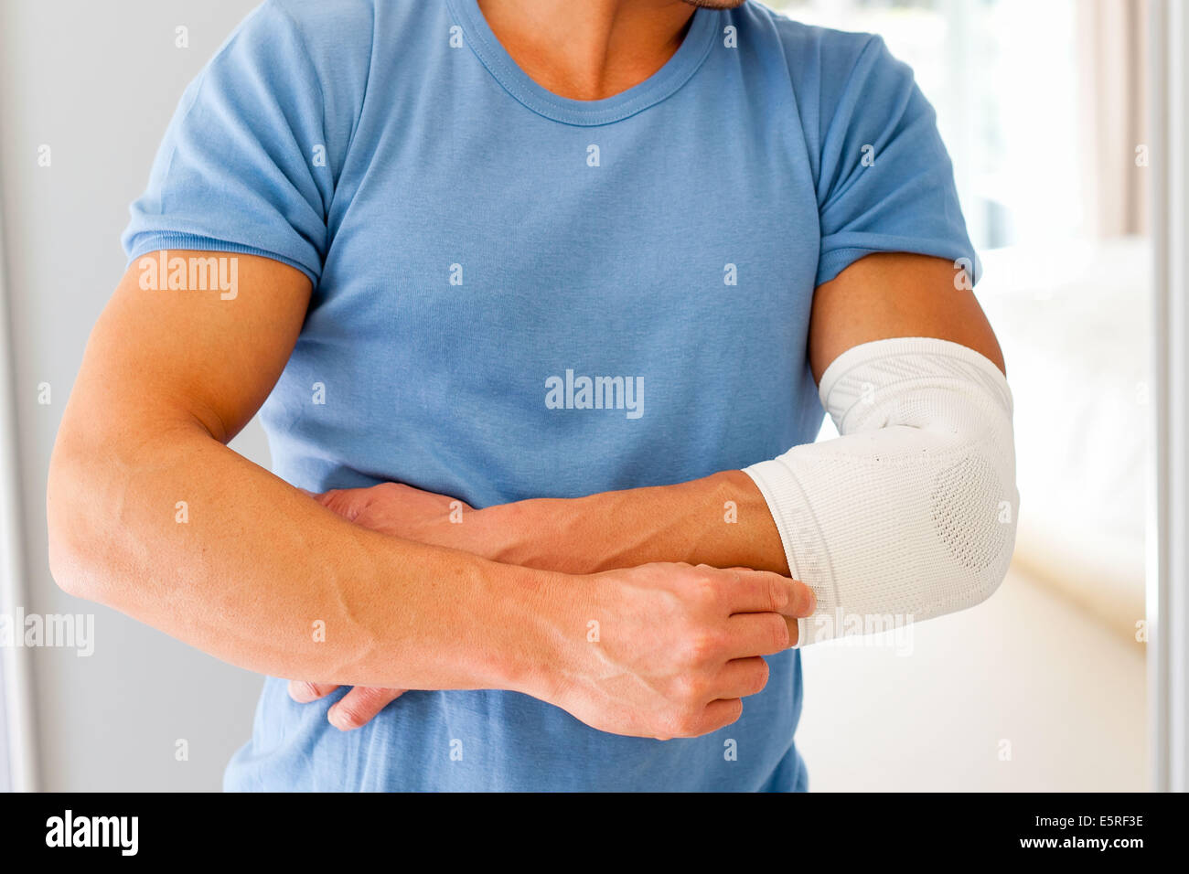Uomo che indossa un supporto a gomito. Foto Stock