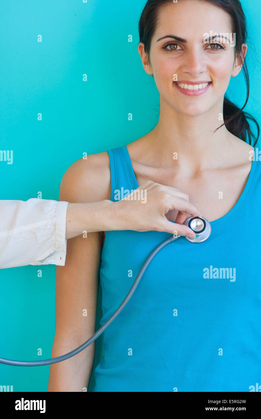 Medico esaminando una donna con uno stetoscopio. Foto Stock