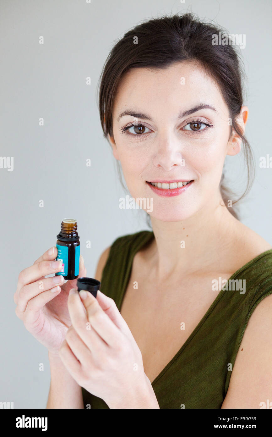 Donna che mantiene una bottiglia di olio essenziale. Foto Stock