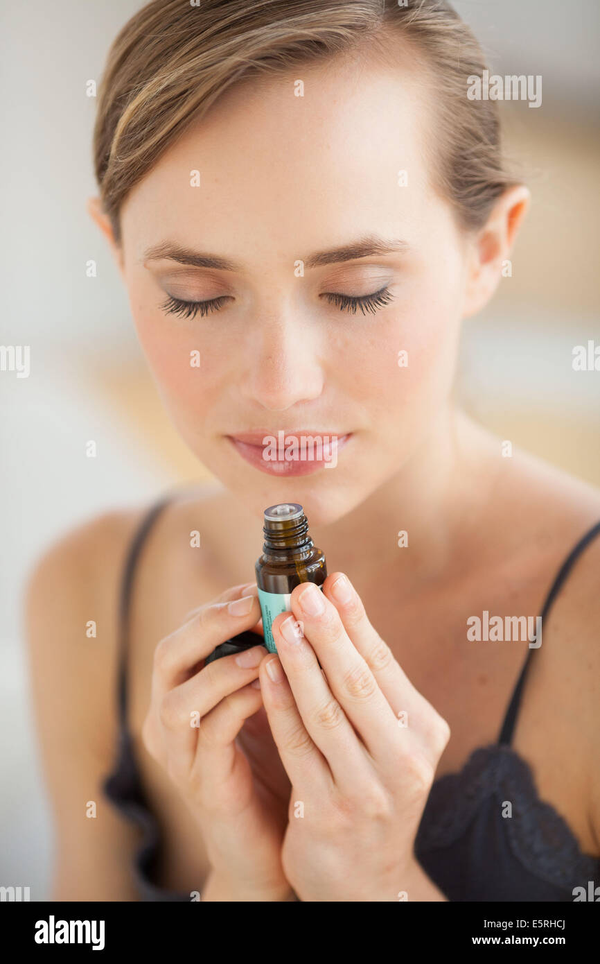 Donna annusare una bottiglia di olio essenziale. Foto Stock