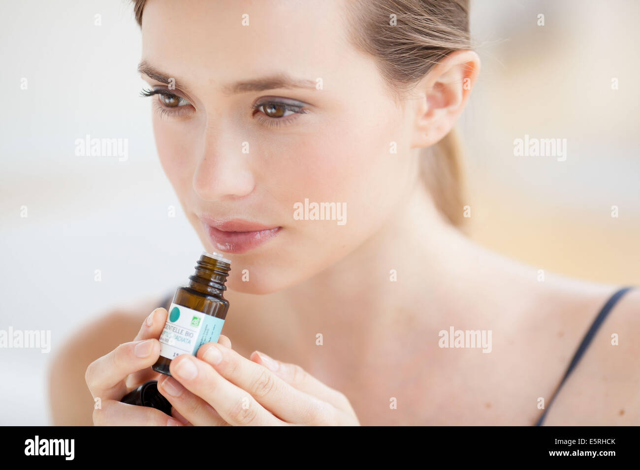 Donna annusare una bottiglia di olio essenziale. Foto Stock