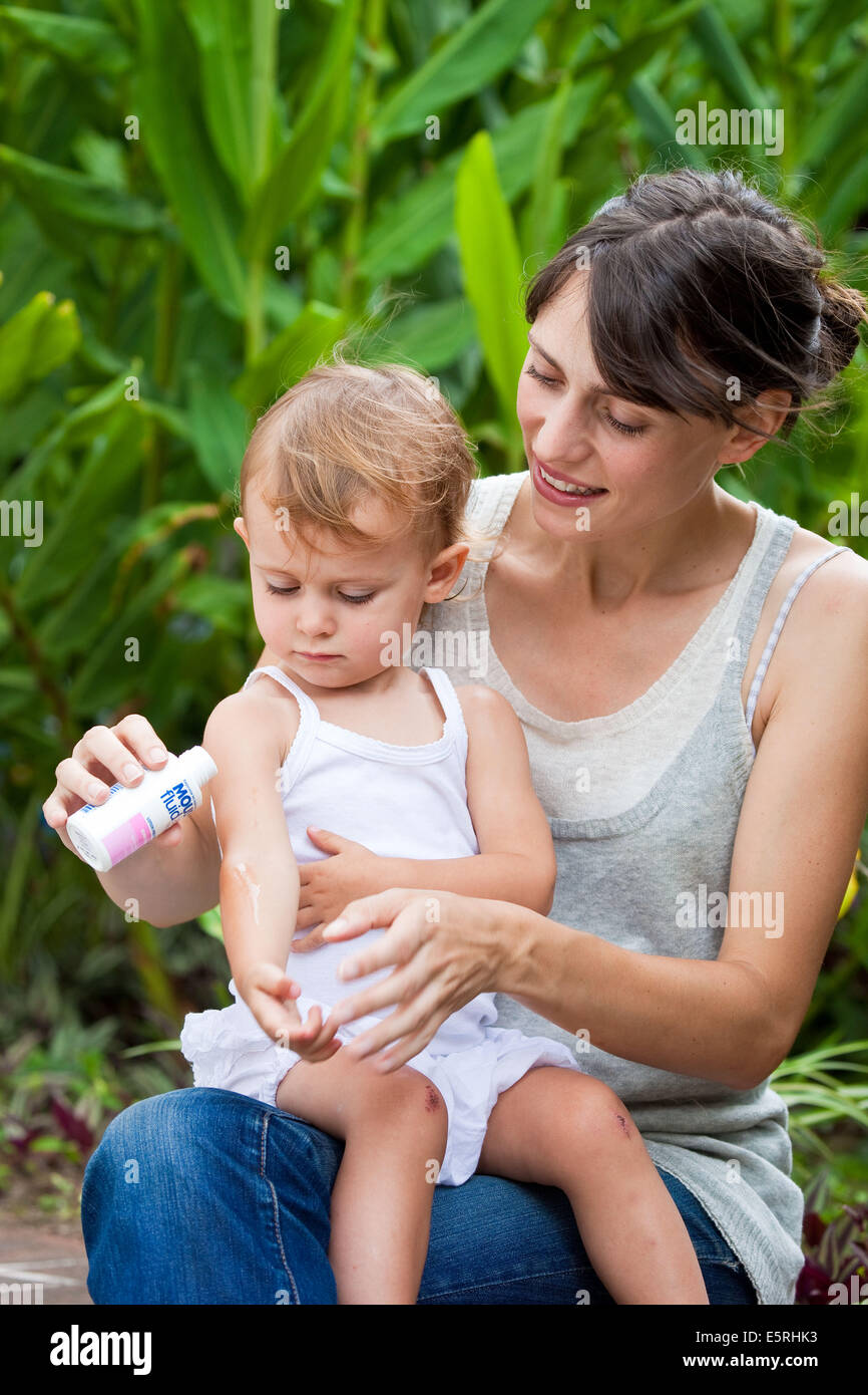 Madre applicando un anti-zanzara crema sulla pelle per il suo 20 mesi baby. Foto Stock