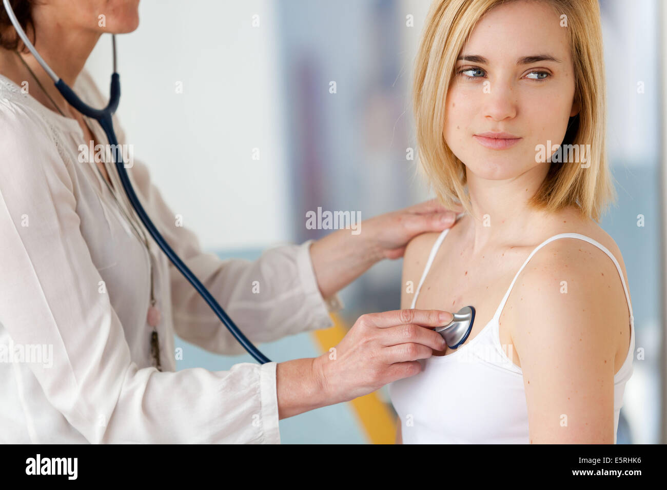 Medico di esaminare un paziente femmina con uno stetoscopio. Foto Stock