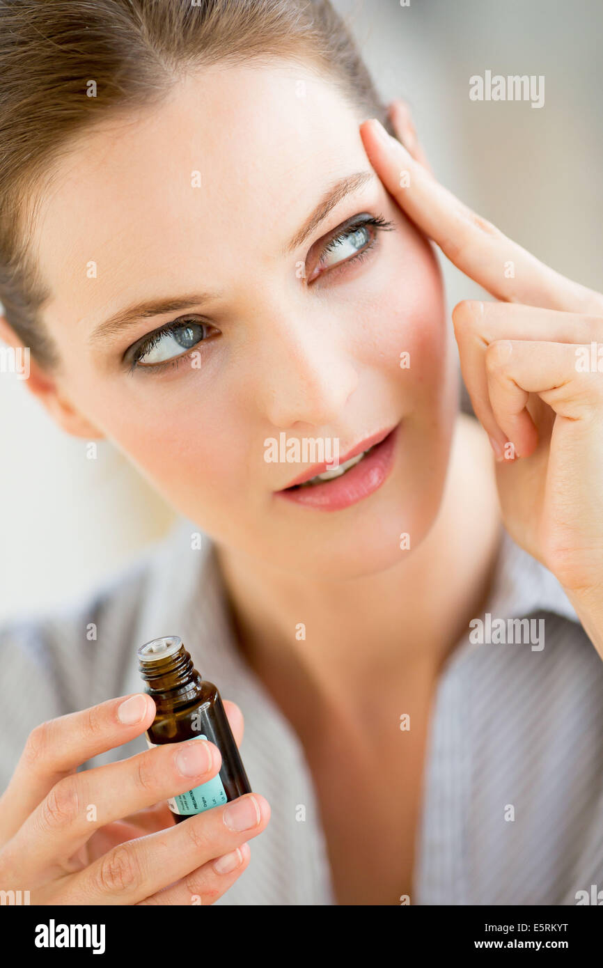 Donna di applicare olio essenziale sui suoi templi. Foto Stock