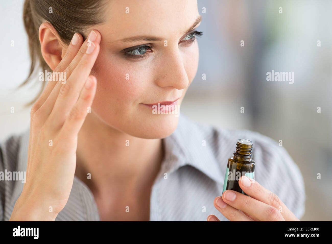 Donna di applicare olio essenziale sui suoi templi. Foto Stock