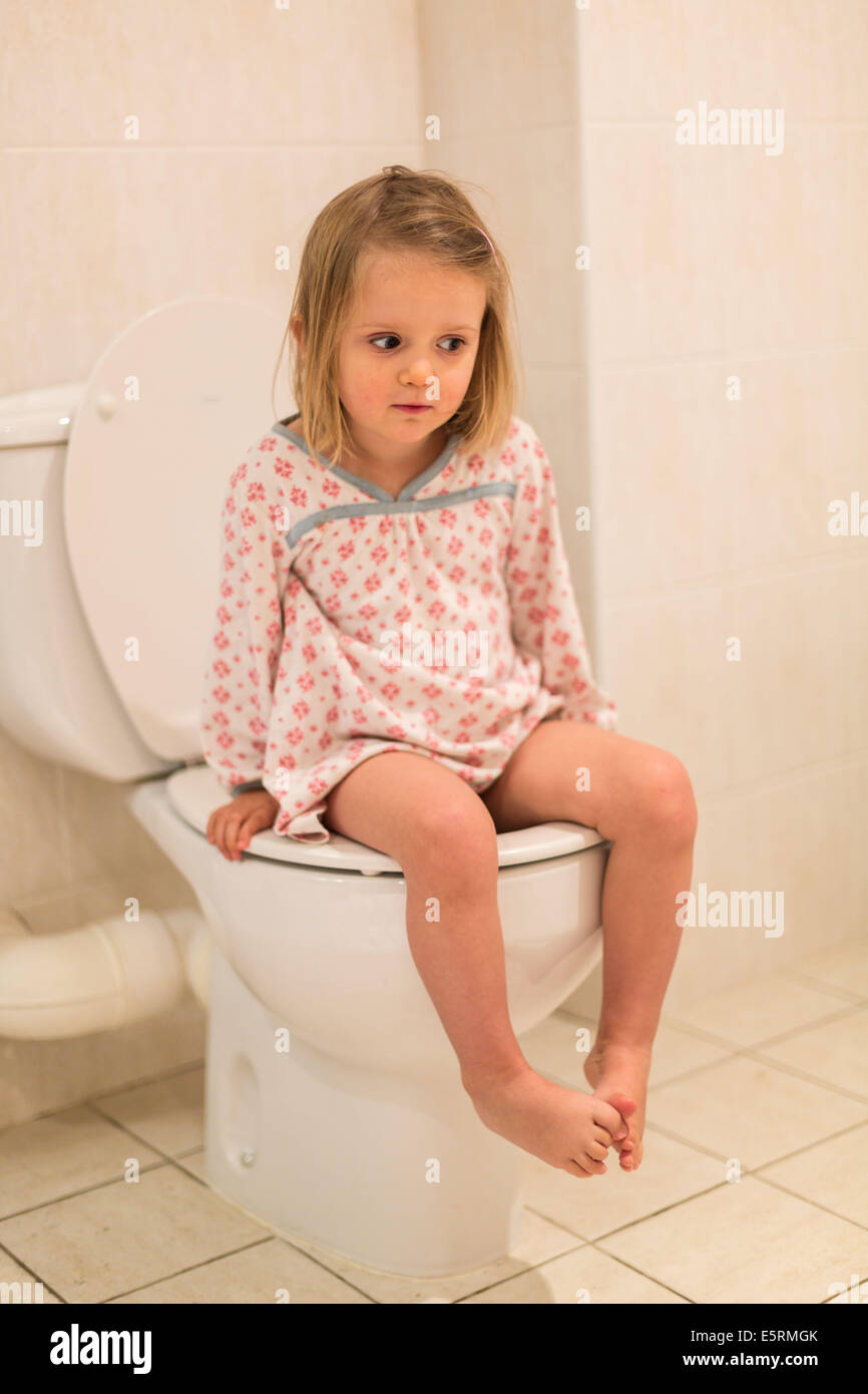 Servizi igienici formazione. 3 anno vecchia ragazza utilizzando un adulto wc aver progredito dall'uso di un bambino vasino. Foto Stock