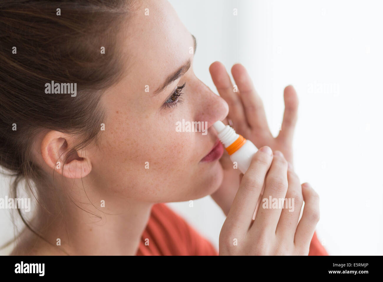 Donna che utilizza uno spray nasale per controllare la rinite. Foto Stock