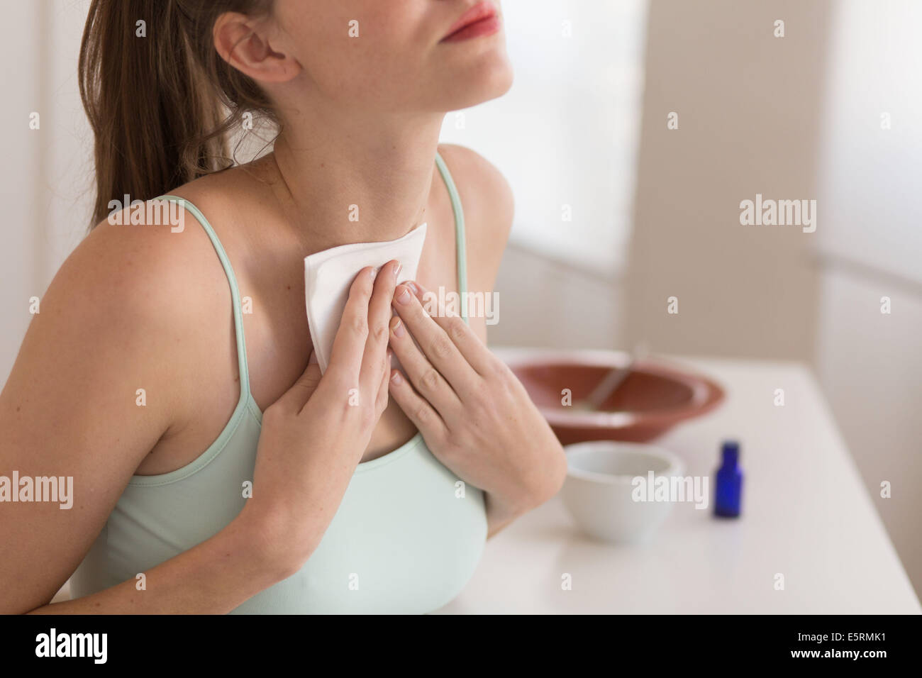 Donna di applicare un impiastro sulla tiroide. Foto Stock