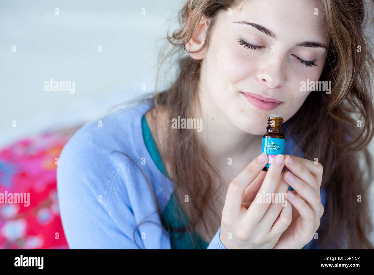 Donna annusare una bottiglia di olio essenziale. Foto Stock