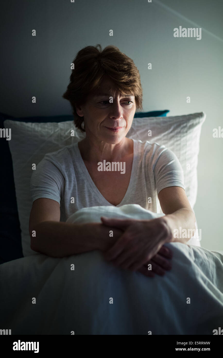 Inquieto donna si siede sul letto non riesce a dormire. Foto Stock