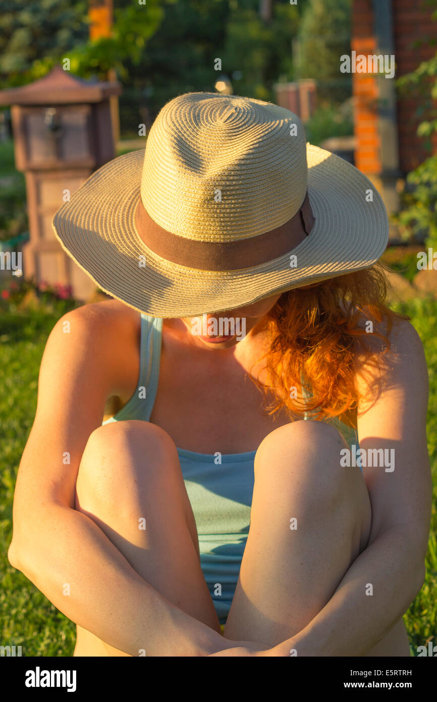 Hipster ragazza essendo timido e nasconde il suo volto dietro un cappello. Godendo di una bella e soleggiata giornata estiva Foto Stock