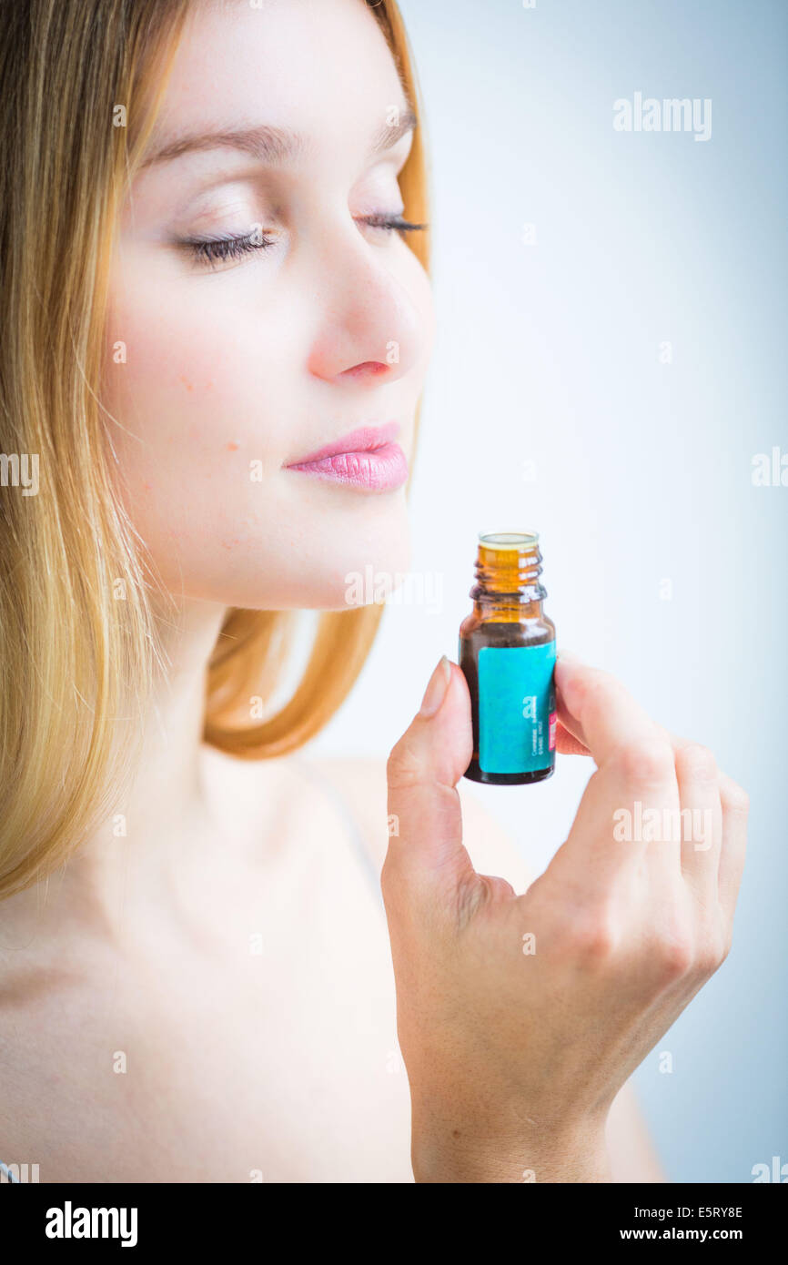 Donna annusare una bottiglia di olio essenziale. Foto Stock